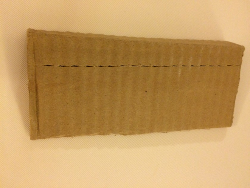 Score your cardboard with an exacto knife or scissor edge and it will easily fold like you need it to. The score should be on the outside, not the inside.